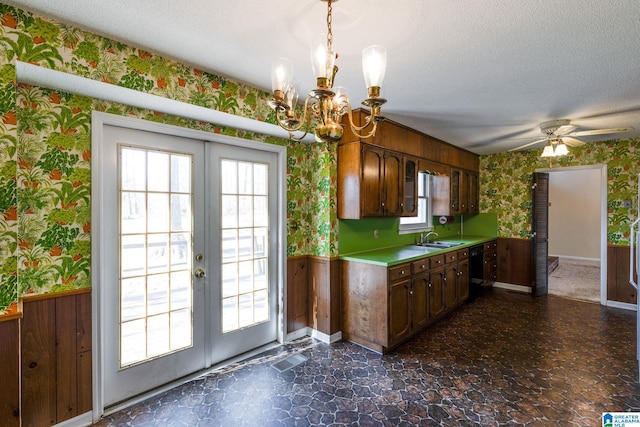 kitchen featuring wallpapered walls, wainscoting, light countertops, a textured ceiling, and french doors