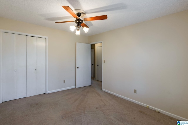 unfurnished bedroom with carpet floors, a textured ceiling, baseboards, and a closet