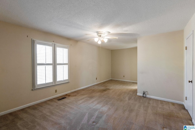 empty room with ceiling fan, a textured ceiling, carpet flooring, visible vents, and baseboards