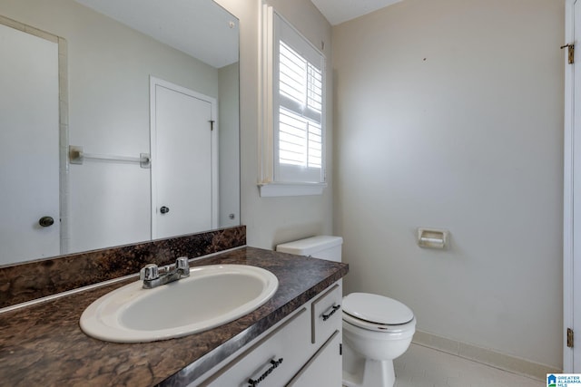 bathroom with toilet, tile patterned flooring, baseboards, and vanity