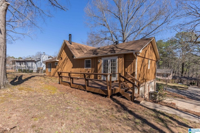 exterior space featuring a deck, a garage, a shingled roof, french doors, and board and batten siding