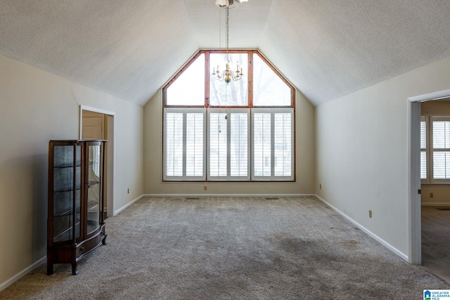 interior space featuring a textured ceiling, a notable chandelier, baseboards, vaulted ceiling, and carpet