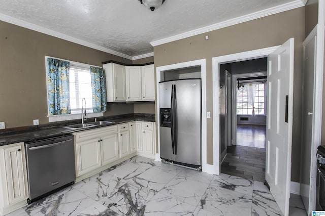 kitchen with a textured ceiling, a sink, appliances with stainless steel finishes, dark countertops, and crown molding