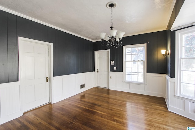 unfurnished dining area featuring dark wood-type flooring, visible vents, a notable chandelier, and crown molding