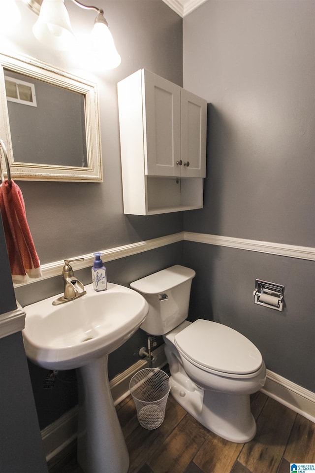 half bath with toilet, baseboards, and wood finished floors