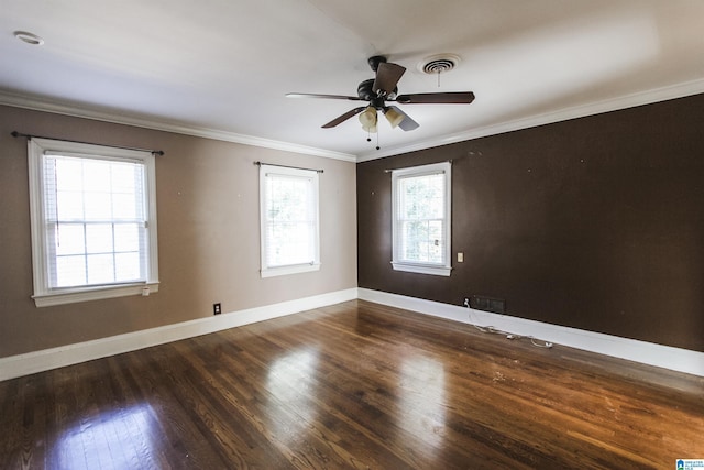 spare room with ceiling fan, visible vents, baseboards, ornamental molding, and dark wood-style floors