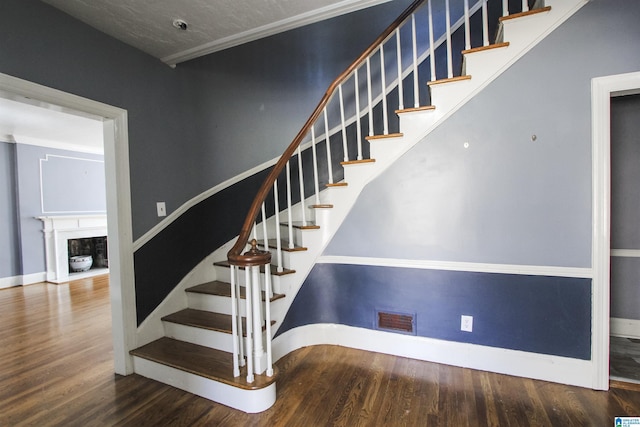 stairway with a fireplace, baseboards, and wood finished floors