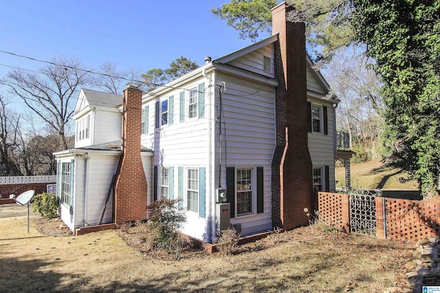 view of side of home featuring fence and a chimney