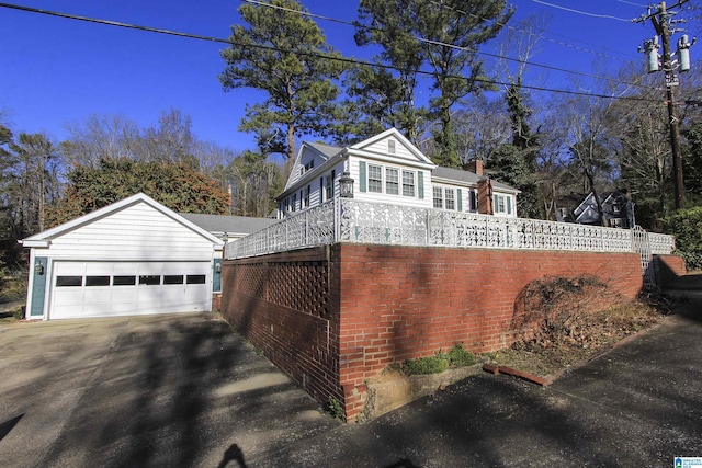 view of side of property featuring brick siding, driveway, an attached garage, and fence