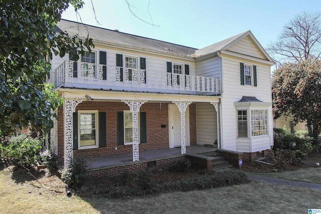 view of front of house featuring a porch, brick siding, and a balcony