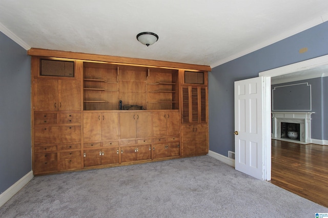 unfurnished room with a fireplace with flush hearth, light colored carpet, crown molding, and baseboards