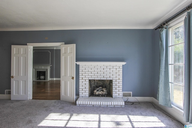 unfurnished living room with carpet flooring, visible vents, baseboards, ornamental molding, and a brick fireplace