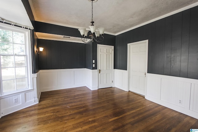 unfurnished dining area featuring a chandelier, ornamental molding, dark wood finished floors, and visible vents