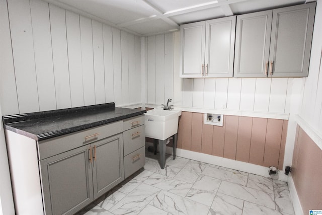 clothes washing area with marble finish floor, hookup for a washing machine, cabinet space, a sink, and baseboards