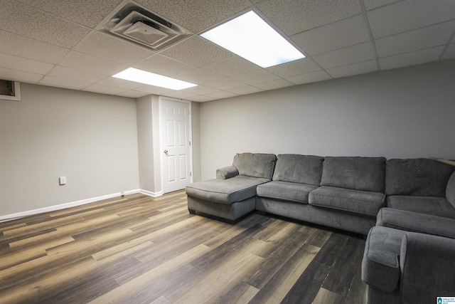 living room with a paneled ceiling, visible vents, baseboards, and wood finished floors