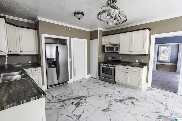 kitchen with stainless steel appliances, a sink, white cabinetry, ornamental molding, and dark countertops