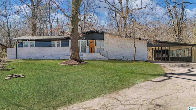 mid-century home with a carport, stone siding, driveway, and a front lawn