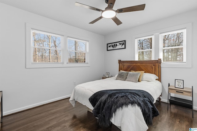 bedroom featuring dark wood-type flooring, multiple windows, a ceiling fan, and baseboards