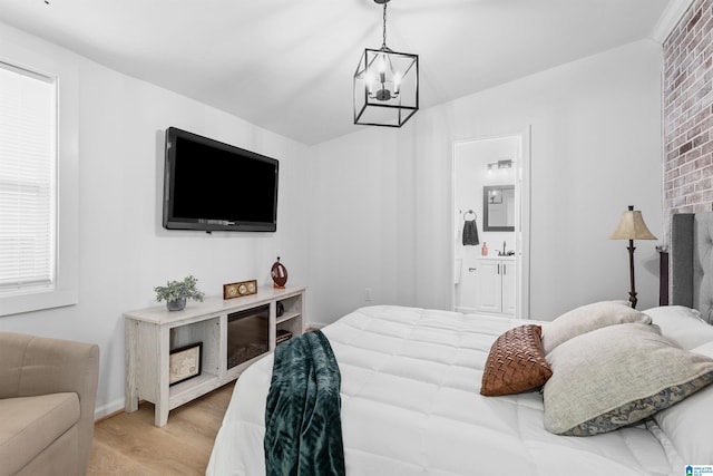 bedroom featuring a sink, ensuite bath, light wood-style flooring, and an inviting chandelier