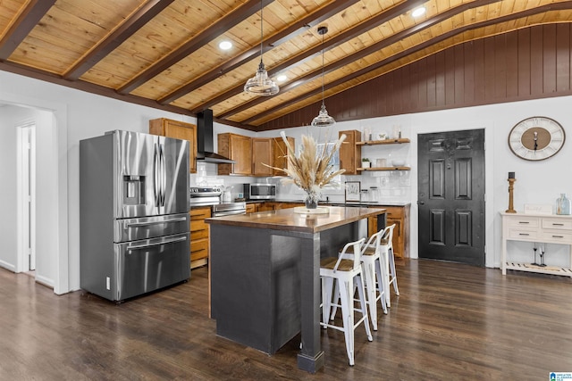 kitchen with a kitchen island, hanging light fixtures, appliances with stainless steel finishes, wall chimney range hood, and open shelves