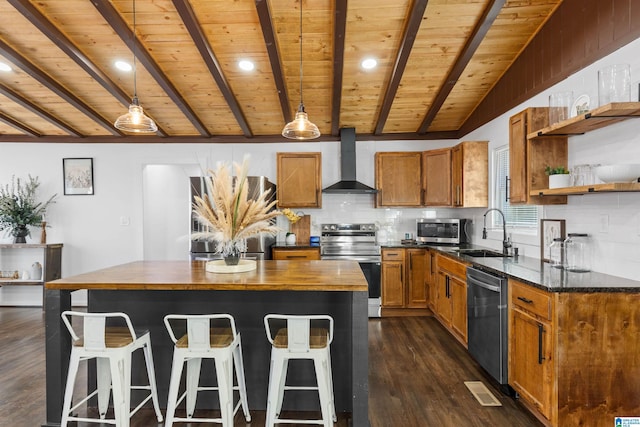 kitchen with decorative light fixtures, open shelves, appliances with stainless steel finishes, a sink, and wall chimney exhaust hood