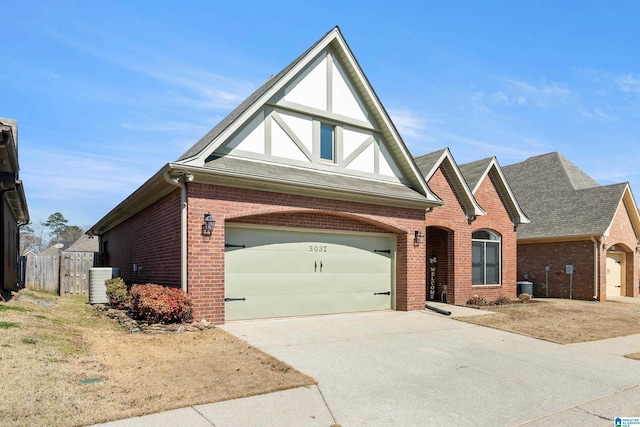 tudor-style house with central air condition unit, a garage, brick siding, fence, and driveway