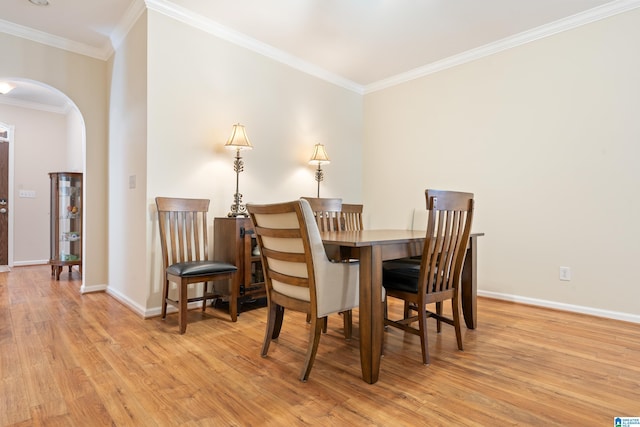 dining space with ornamental molding, arched walkways, baseboards, and wood finished floors