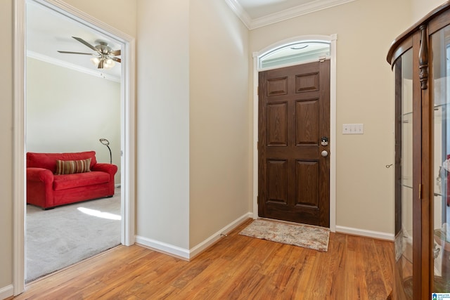 foyer featuring light wood finished floors, a ceiling fan, baseboards, and crown molding