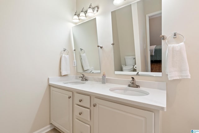 bathroom featuring toilet, double vanity, and a sink