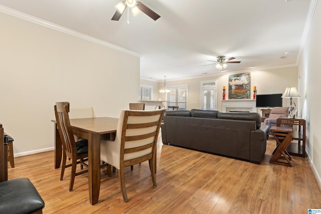 dining room featuring light wood-style flooring, ornamental molding, baseboards, and ceiling fan with notable chandelier