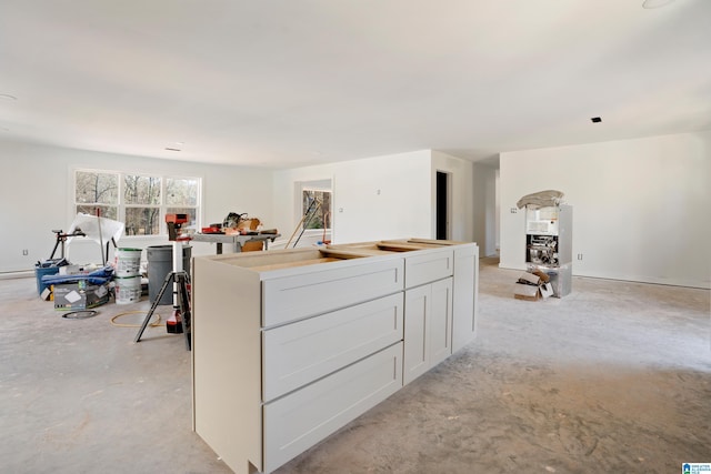 kitchen with concrete floors, a kitchen island, and white cabinets