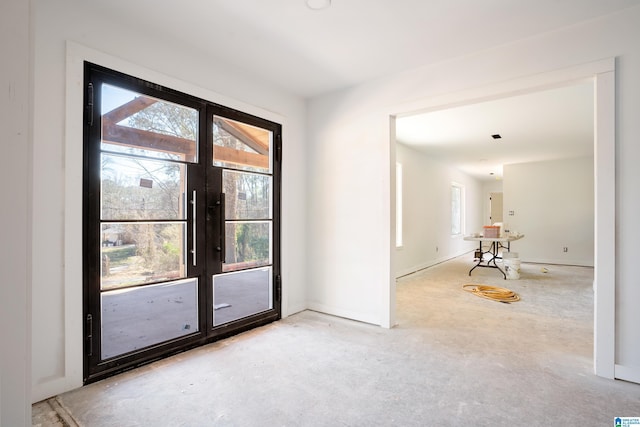 doorway with unfinished concrete floors, baseboards, and french doors