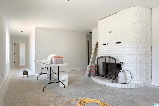 living room with a fireplace, unfinished concrete flooring, and baseboards