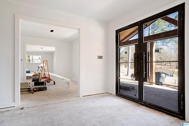 doorway to outside featuring french doors, unfinished concrete flooring, and baseboards