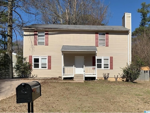 view of front of property featuring covered porch, a front lawn, and a chimney