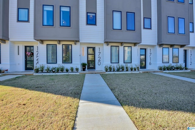 townhome / multi-family property featuring a front lawn and stucco siding