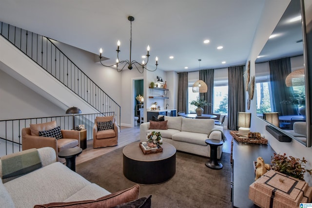 living area featuring a notable chandelier, recessed lighting, stairway, wood finished floors, and baseboards