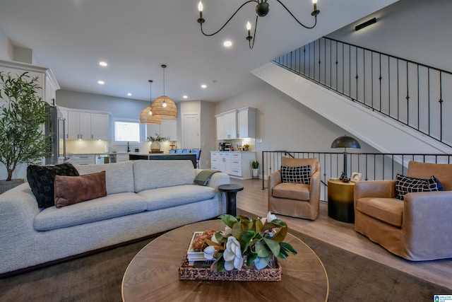 living room featuring recessed lighting, a notable chandelier, and light wood-style flooring