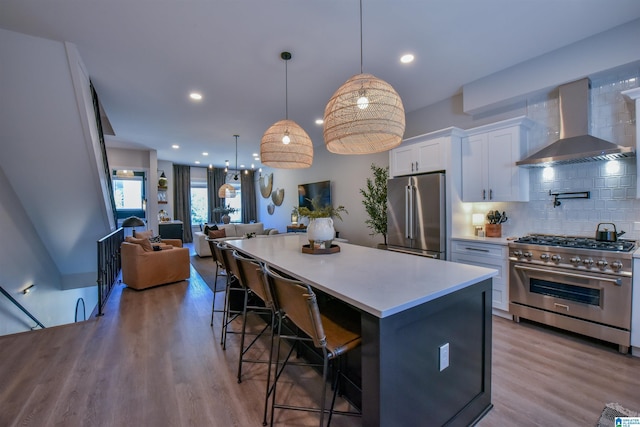 kitchen featuring white cabinetry, open floor plan, light countertops, wall chimney range hood, and high end appliances