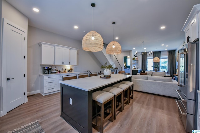 kitchen featuring a breakfast bar area, light countertops, open floor plan, white cabinets, and high end refrigerator