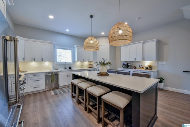 kitchen featuring a center island, light countertops, stainless steel dishwasher, white cabinetry, and a sink