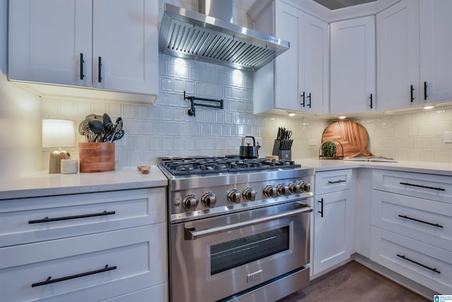 kitchen with white cabinets, light countertops, high end stainless steel range, decorative backsplash, and wall chimney exhaust hood