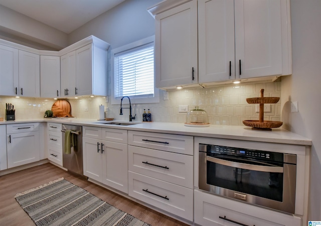 kitchen featuring light countertops, stainless steel appliances, a sink, and white cabinets