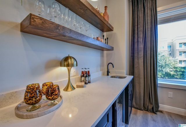 bar featuring beverage cooler, visible vents, wood finished floors, wet bar, and a sink