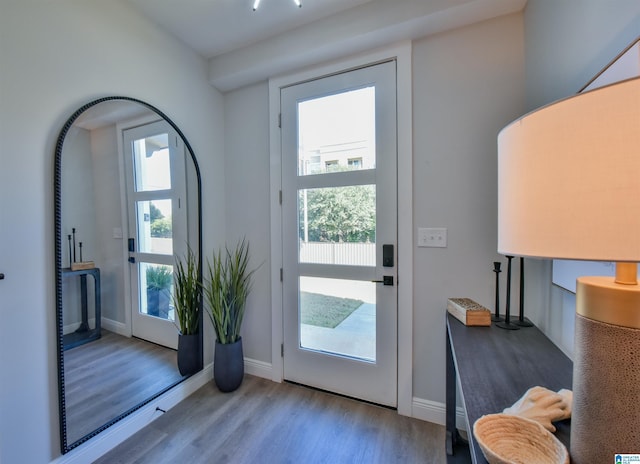 doorway with light wood-type flooring, plenty of natural light, and baseboards