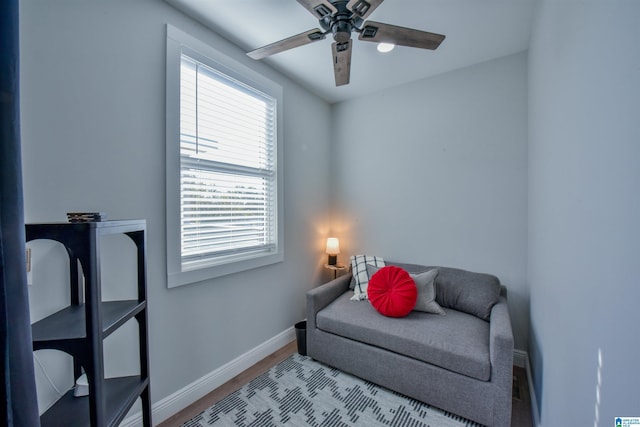 sitting room with ceiling fan and baseboards