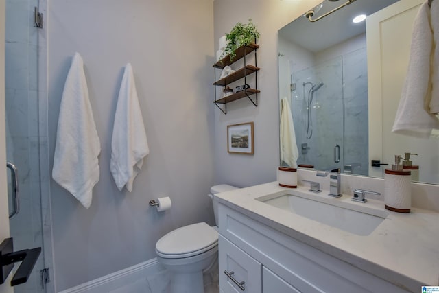 bathroom with baseboards, toilet, a shower stall, and vanity