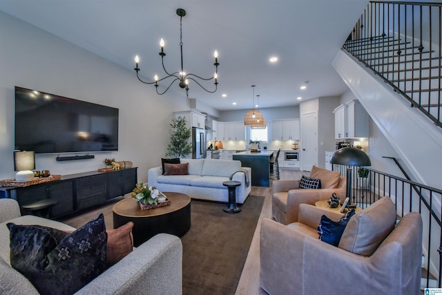 living area with dark wood-type flooring, stairway, an inviting chandelier, and recessed lighting