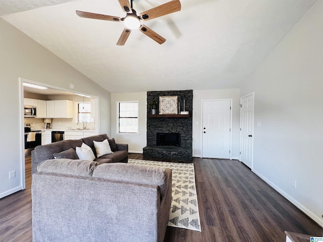 living room featuring baseboards, a ceiling fan, dark wood-style floors, vaulted ceiling, and a stone fireplace