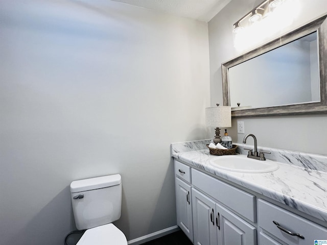 bathroom with baseboards, vanity, and toilet